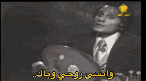 a man in a suit and tie playing a musical instrument with arabic writing on the bottom