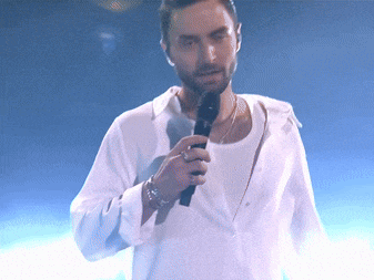 a man singing into a microphone with a white shirt on