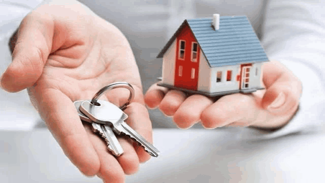 a person is holding a model house and keys .