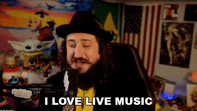 a man with a beard is sitting in front of a microphone and saying i love live music