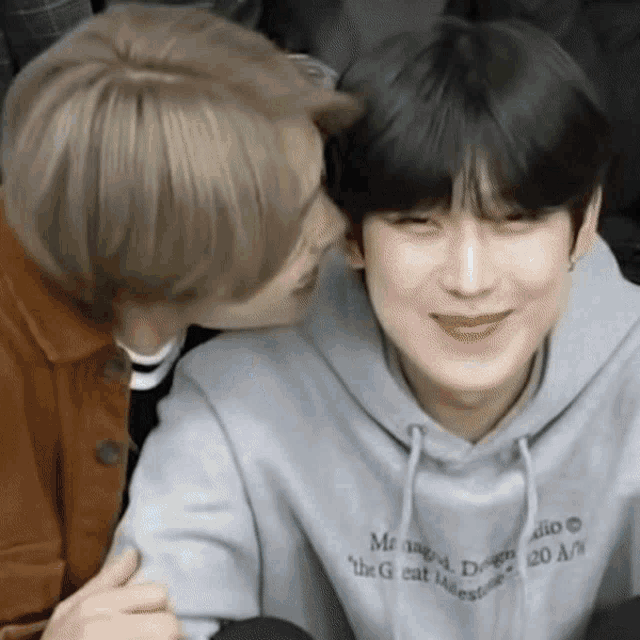 a man is kissing another man on the cheek while wearing a hoodie that says the greatest