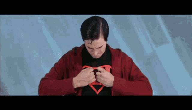 a man in a superman costume is opening his jacket .