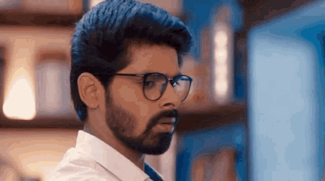 a man with glasses and a beard looks to his left