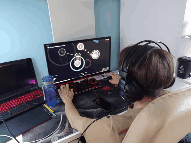 a person wearing headphones playing a video game on a lenovo laptop