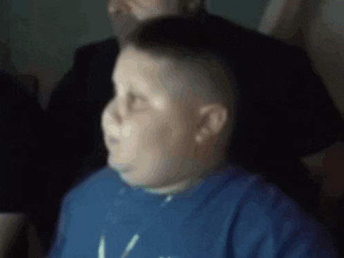 a blurry picture of a boy wearing a blue shirt that has the letter v on it