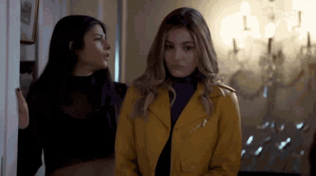 two women are standing next to each other in a room .