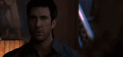 a man is standing in a dark room with a lamp in front of him