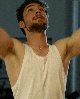 a man in a white tank top is looking up