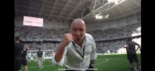a man in a white shirt stands on a soccer field in front of a crowd