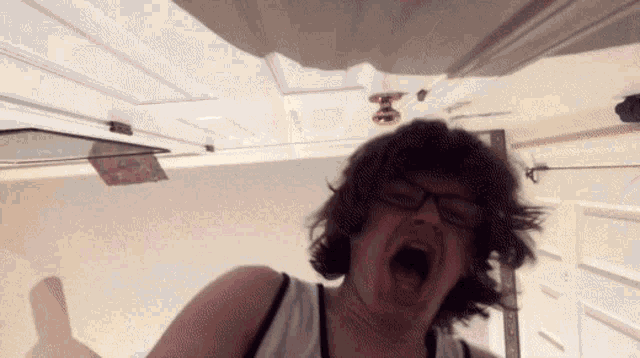 a woman with glasses is making a funny face with her mouth wide open