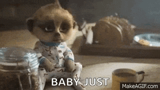 a meerkat in pajamas is sitting on a table next to a cup of coffee .