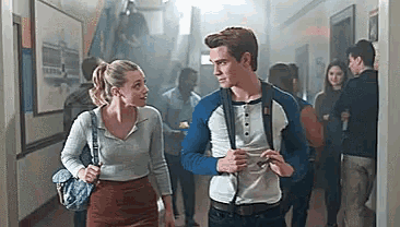 a man and a woman are walking down a hallway in a school .