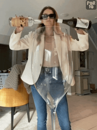 a woman is pouring a bottle of wine into a large wine glass that says por 10 on the bottom