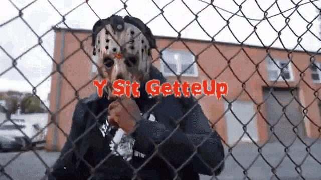 a person wearing a hockey mask behind a chain link fence with the words " y sit getteup " written on it