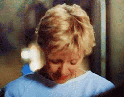 a woman wearing a blue scrub top is smiling and looking down