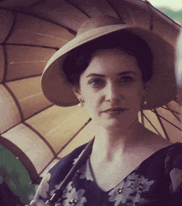 a woman wearing a hat holds an umbrella in her hand