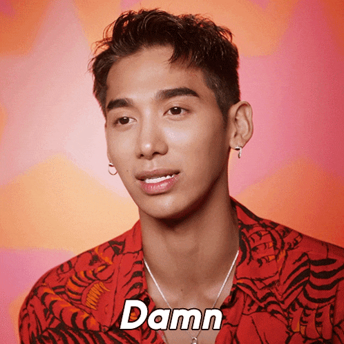 a man wearing a red shirt and a necklace says " damn "