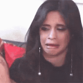 a woman is crying while sitting on a couch with her mouth open .