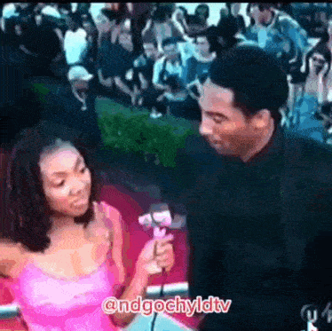 a woman in a pink dress is being interviewed by a man in a black suit on a red carpet .
