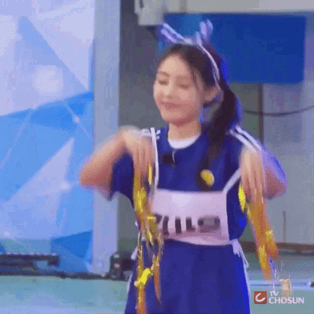 a girl is wearing a blue shirt and a pink vest with the word pills on it .