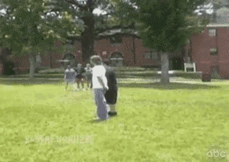 a group of people are standing in a grassy field with abc written in the corner