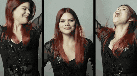 a woman with red hair is smiling and laughing with her arms in the air