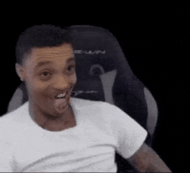 a man in a white shirt is sitting in a chair and making a surprised face .