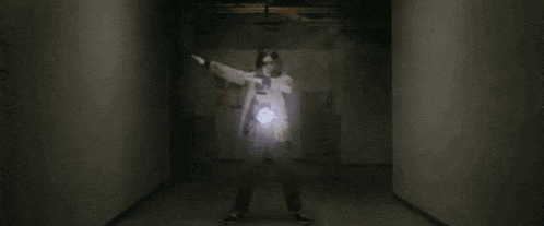 a person is standing in a dark hallway with a light coming out of their chest .