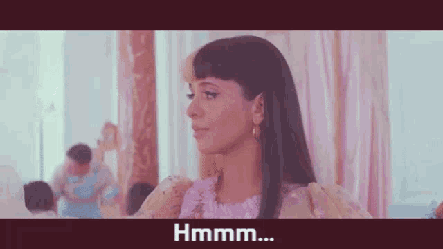 a woman in a pink dress is standing in a room with a man standing behind her .