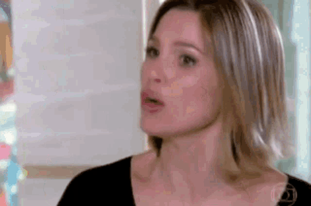 a close up of a woman 's face with her mouth open and a black shirt on .