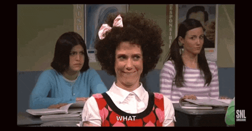 a woman sitting in a classroom with a sign that says what