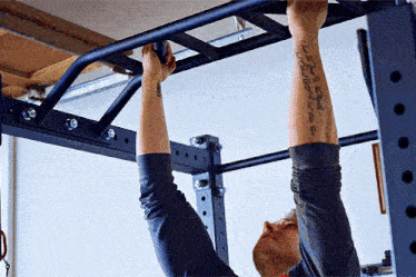 a man with a tattoo on his arm is doing a pull up exercise
