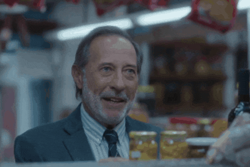 a man with a beard looks at jars of food