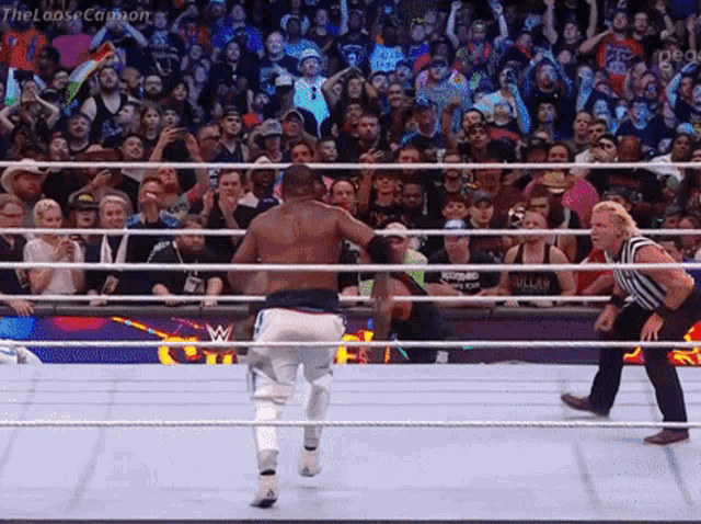 a wrestling match is going on in front of a crowd and a referee .