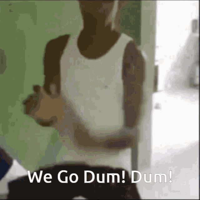 a man in a white tank top is standing in front of a door and says we go dum dum !