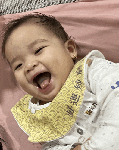 a baby wearing a bib with chinese writing on it is smiling