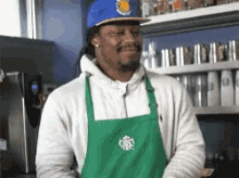 a man wearing a green apron and a starbucks hat