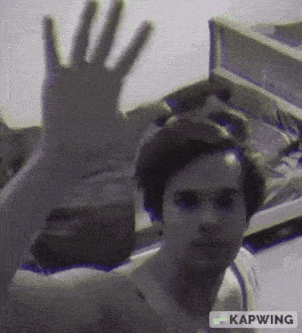 a man is waving his hand in front of a camera .