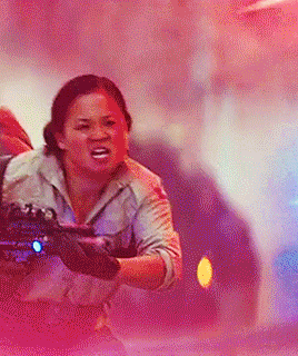a woman is running with a gun in her hand while a car is behind her