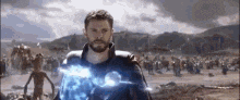 a man with a beard is standing in front of a crowd of people in a field holding a lightning bolt .