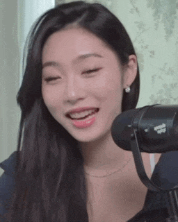 a woman is smiling in front of a microphone while wearing earrings .