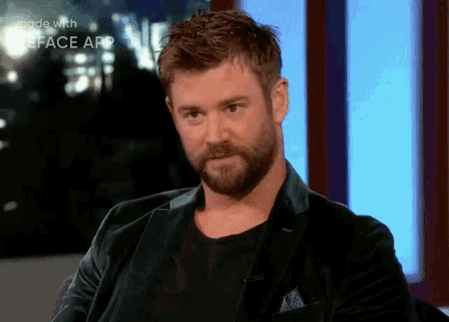 a man with a beard is wearing a black jacket and a black shirt