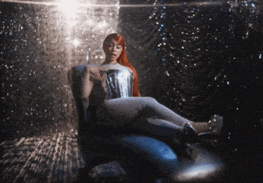 a woman with long red hair is sitting in a chair with her legs crossed