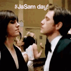 a man in a tuxedo and a woman in a black dress are looking at each other