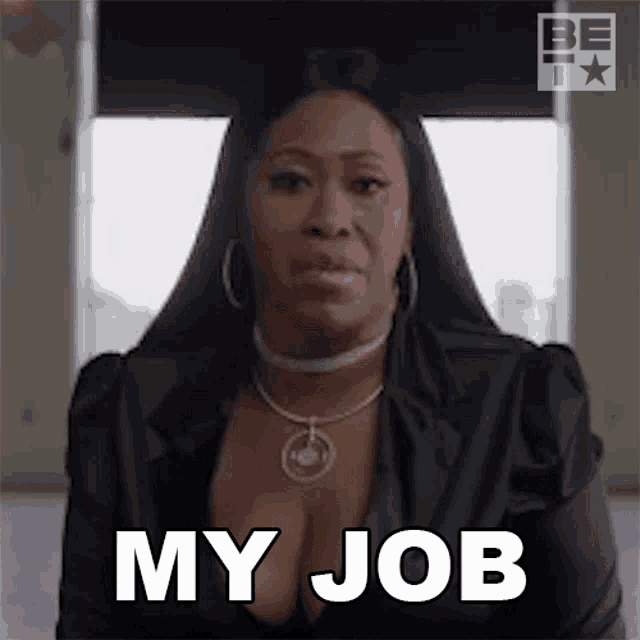 a woman is sitting in front of a window and making a funny face while saying `` my job '' .
