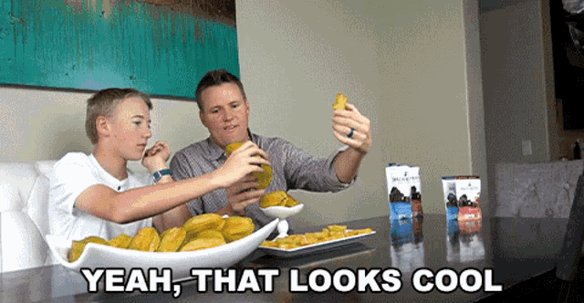 a man and a boy are sitting at a table with a bowl of food and the words yeah that looks cool