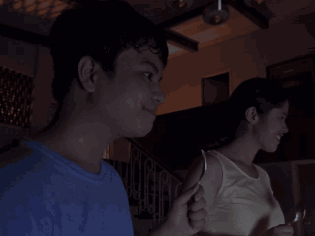 a man in a blue shirt holds a spoon in front of a woman