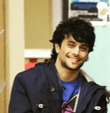 a young man wearing a blue shirt and a blue jacket is smiling .
