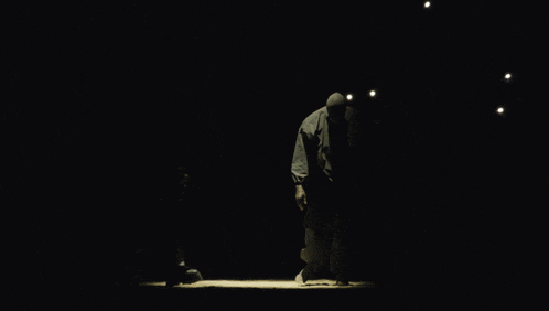 a man in a hooded jacket stands in the dark