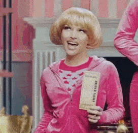 a woman in a pink velvet jacket is holding a piece of chocolate .